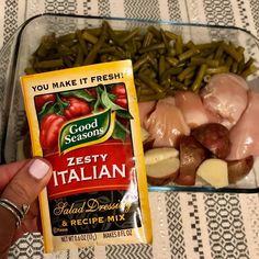 a person holding a packet of frozen food next to a container of green beans and potatoes
