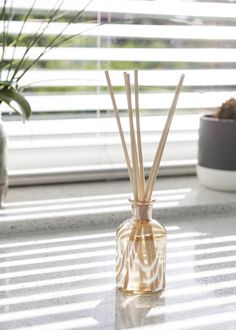 a glass bottle with reeds in it sitting on a window sill