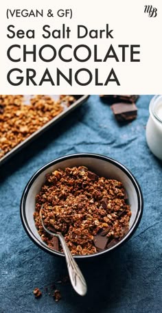 a bowl filled with granola next to a glass of milk and spoon on a blue cloth