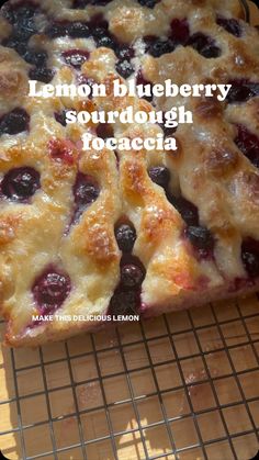 lemon blueberry sourdough focaccia on a cooling rack with the words, lemon blueberry sourdough focaccca