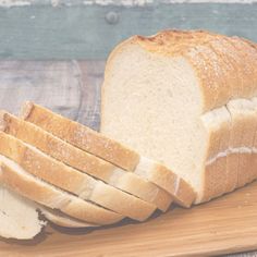 a loaf of white bread sitting on top of a wooden cutting board