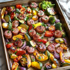 a pan filled with sausages, vegetables and broccoli on top of a table