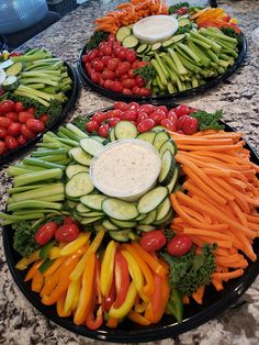 four platters filled with different types of veggies on top of a table