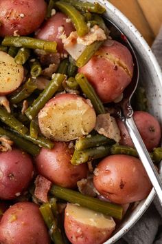 A bowl of red potatoes and green beans with a serving spoon.