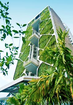a tall building with plants growing on it's side and the top part of its roof
