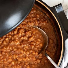 a pot filled with baked beans on top of a table next to a white towel