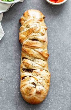 a long loaf of bread sitting on top of a table next to a bowl of salad