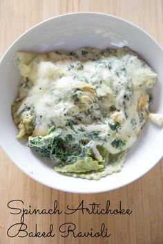 spinach artichoke baked ravioli in a white bowl on a wooden table