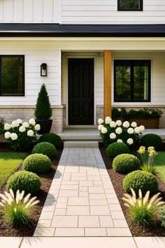 a house with white flowers and bushes in the front yard