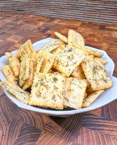 a white bowl filled with cheesy crackers on top of a wooden table