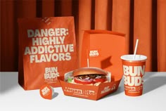 an orange dunkin'donuts box with a burger inside it and two cups