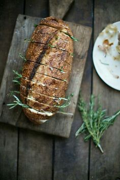 a loaf of bread sitting on top of a wooden cutting board next to a plate