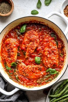 a pan filled with meat covered in tomato sauce and garnished with basil leaves