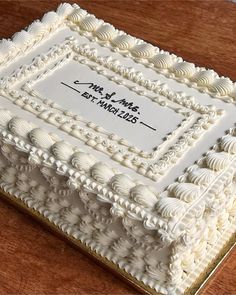 a square cake with white frosting on a wooden table