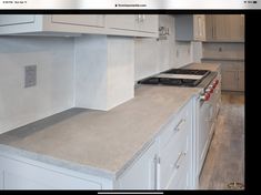 a kitchen with white cabinets and gray counter tops