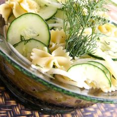 a glass bowl filled with pasta and cucumbers