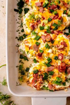 a white casserole dish filled with eggs, ham and green onion garnish