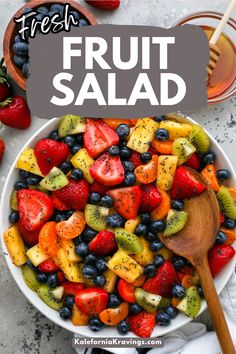 fresh fruit salad in a white bowl with a wooden spoon on the side and text overlay that reads, fresh fruit salad