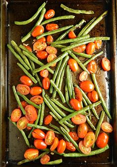green beans and tomatoes on a baking sheet ready to be cooked in the oven for dinner