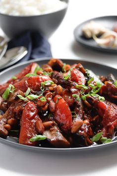 a close up of a plate of food with meat and rice in the background on a table