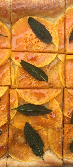sliced oranges with sage leaves on them are arranged in squares and placed on top of each other
