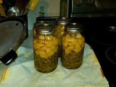 two jars filled with pickles sitting on top of a towel next to an oven