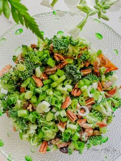 a glass bowl filled with broccoli and nuts