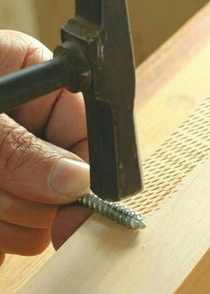 a person is working on a piece of wood with a screwdriver in their hand
