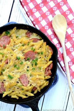 a skillet filled with pasta and sausage on top of a red checkered table cloth