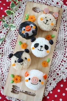 four cupcakes decorated with farm animals on a wooden board