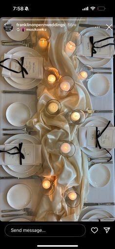 the table is set with white plates and silverware, lit by candlelight candles