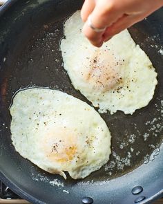 two fried eggs being cooked in a skillet