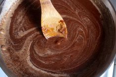 a wooden spoon in a pot filled with brown liquid and melted chocolate on the stove