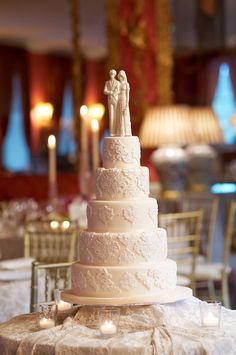 a wedding cake sitting on top of a table with candles in front of the cake