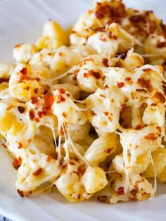 a white plate topped with macaroni and cheese covered in melted cheese on top