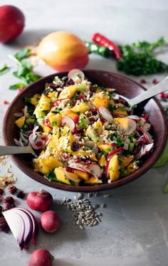 a bowl filled with fruit and vegetables on top of a white table next to other fruits