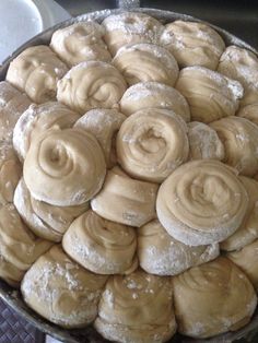 a pan filled with cinnamon rolls covered in powdered sugar on top of a stove