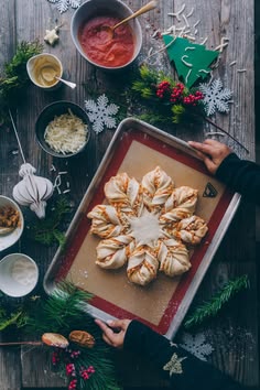 a person holding a tray with some food on it next to bowls and spoons