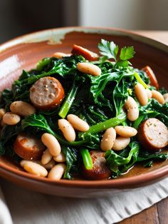 a brown bowl filled with beans and greens on top of a wooden table next to a white napkin