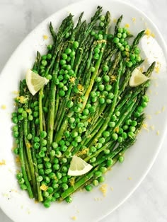 asparagus and lemons on a white plate with salt and pepper sprinkles