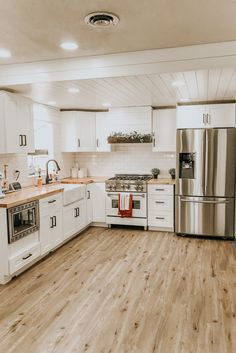 a kitchen with white cabinets and stainless steel appliances, wood flooring and wooden countertops
