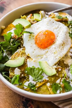 a white bowl filled with vegetables and an egg