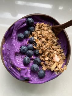 a bowl filled with blueberries and granola on top of a white countertop