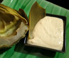 an artichoke and dipping sauce on a green plate