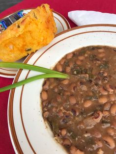 a white plate topped with beans next to a muffin on top of a red table