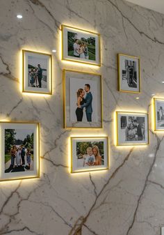 a marble wall with many pictures hanging on it and some lights around the photo frames