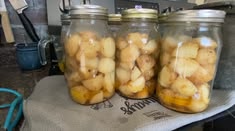three jars filled with food sitting on top of a counter next to a blue and white towel