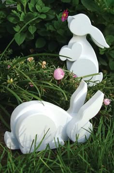 two white plastic rabbits sitting in the grass