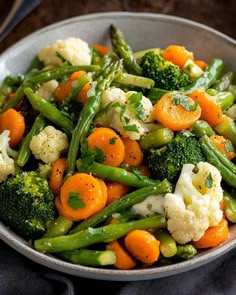 a white bowl filled with broccoli, cauliflower and carrots