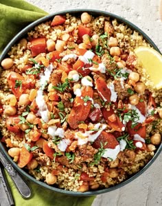 a bowl filled with rice and vegetables on top of a green napkin next to a fork